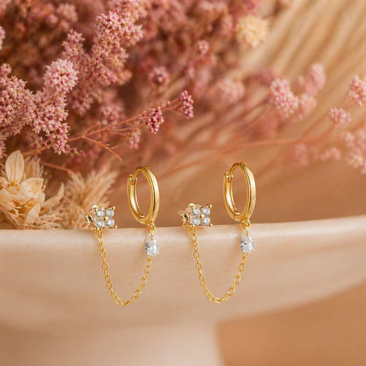 Pair of gold double piercing chain earrings with CZ stud hoop and chain on aesthetic background