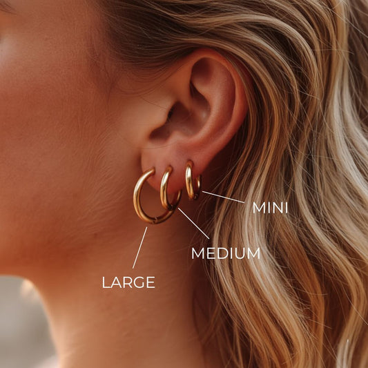 Essential hoop earrings worn on ear by blonde model in a minimal look. With Sizing details