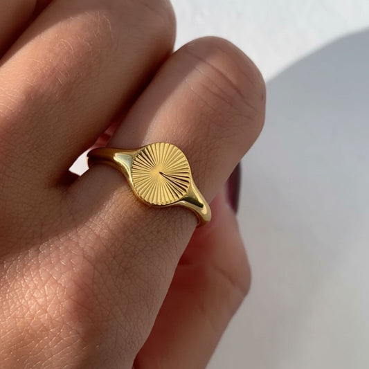 Close-up of tanned hand wearing the Sunbeam Gold Signet Ring – 18K gold waterproof jewelry by Beach Bloom Jewelry.
