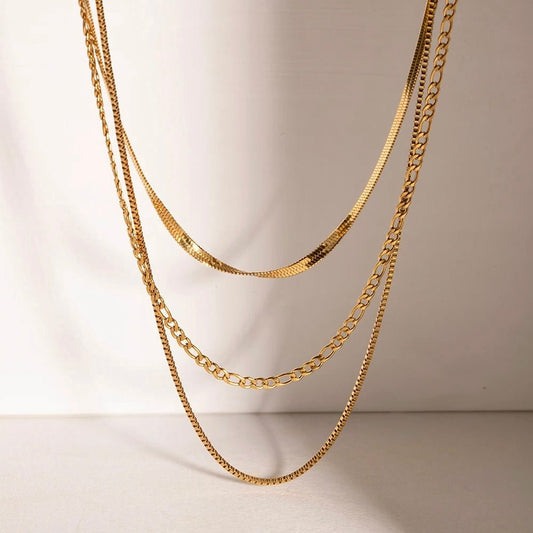 Display of gold layered necklace with three chain styles
