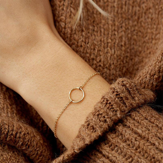 Delicate gold chain bracelet with a textured hoop centerpiece