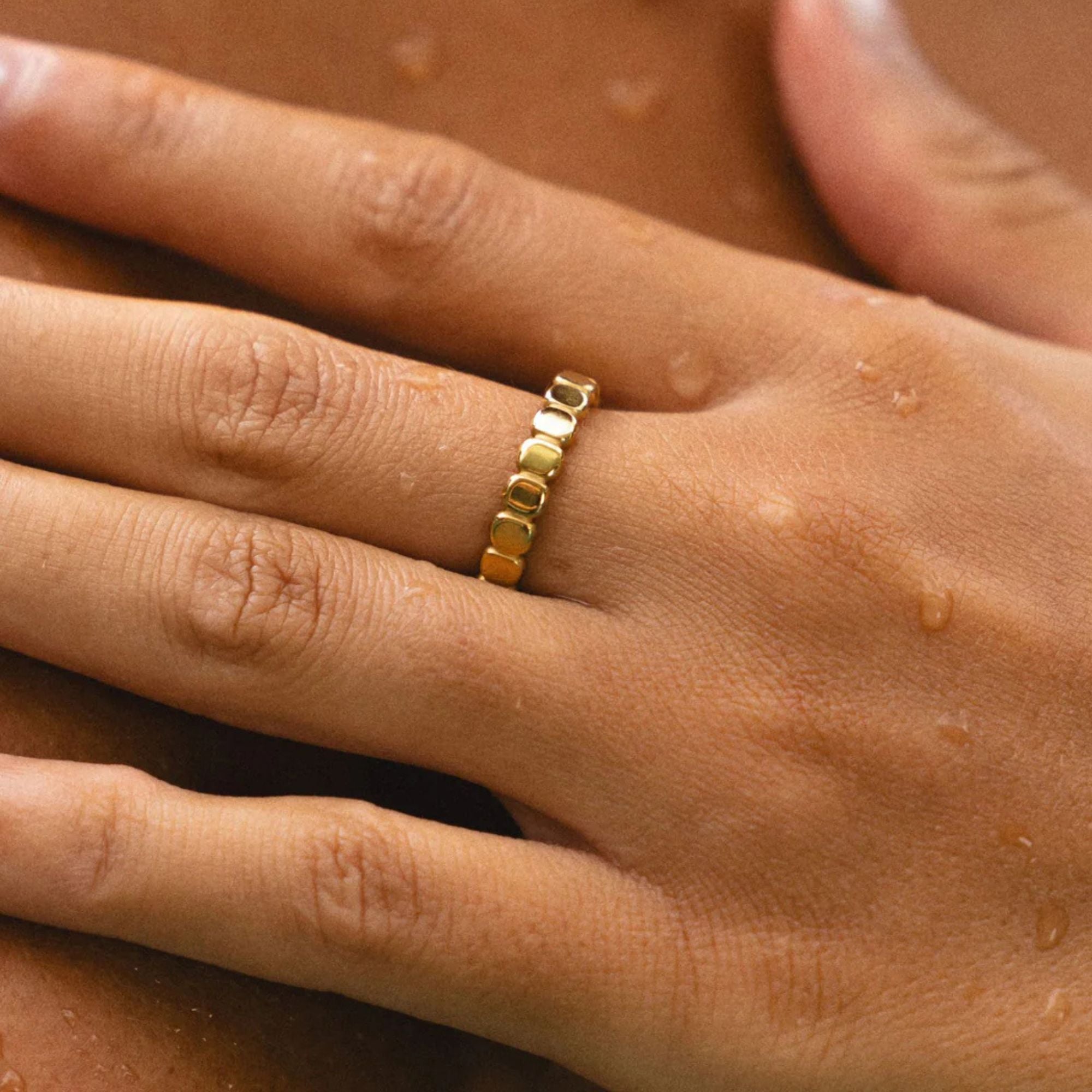 Waterproof golden beaded ring worn on wet hand, ideal for daily wear and stacking style.