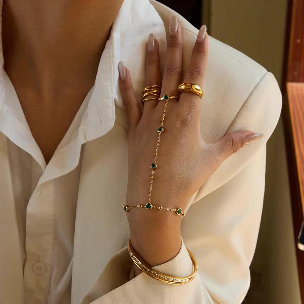Gold hand chain with emerald hearts for elegant, standout styling