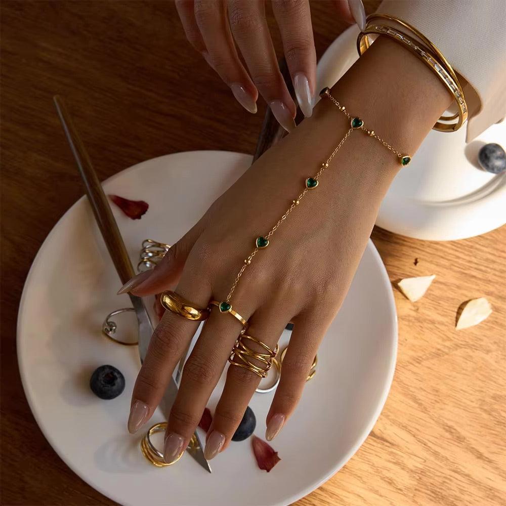 Gold hand chain with emerald hearts for elegant, standout styling