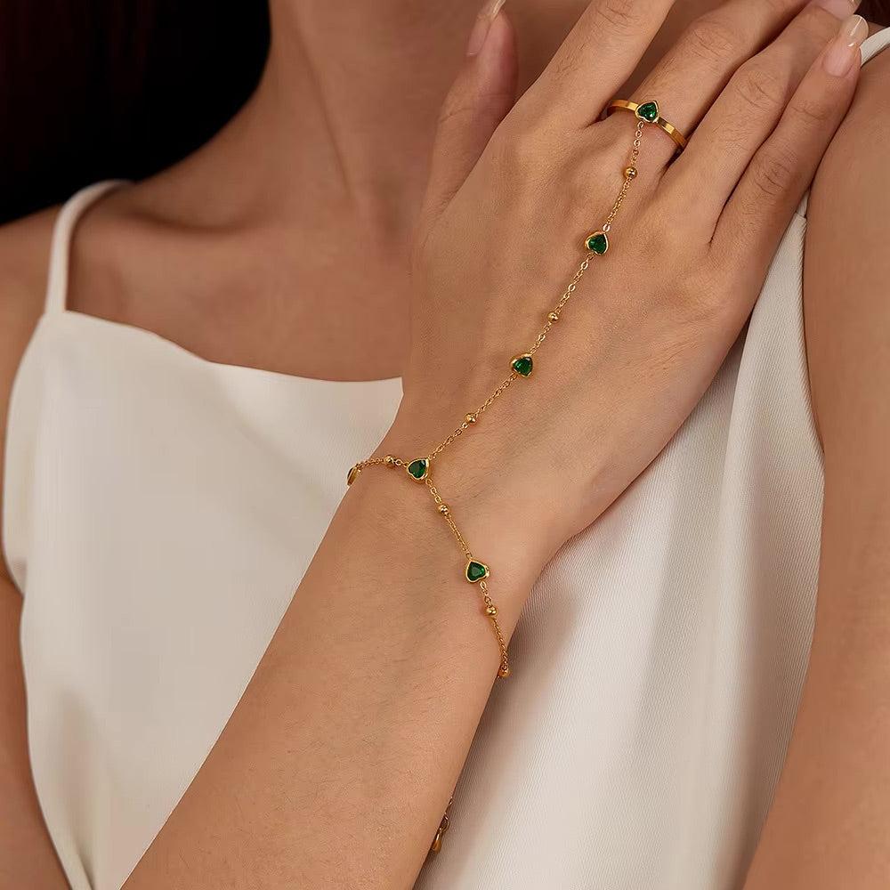 Gold hand chain with emerald hearts for elegant, standout styling