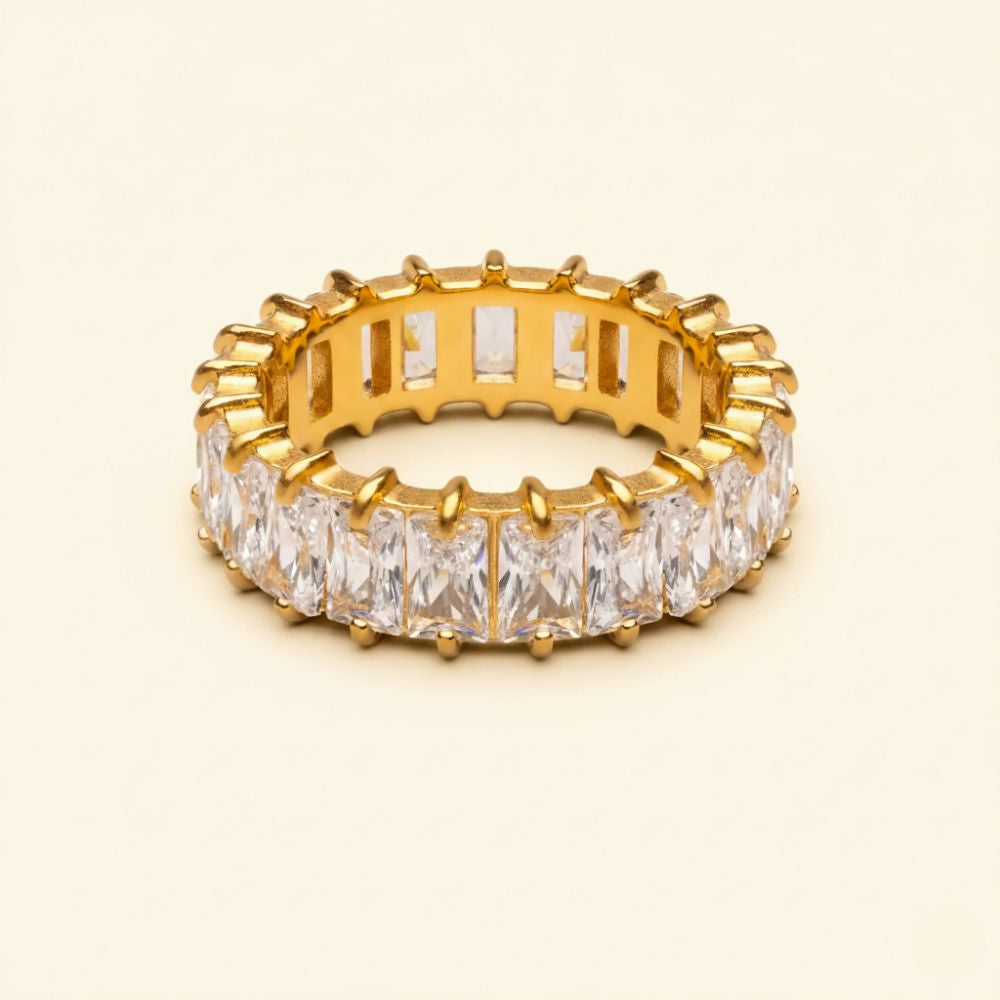 Astra Ring gold crystal baguette eternity band on warm beige background