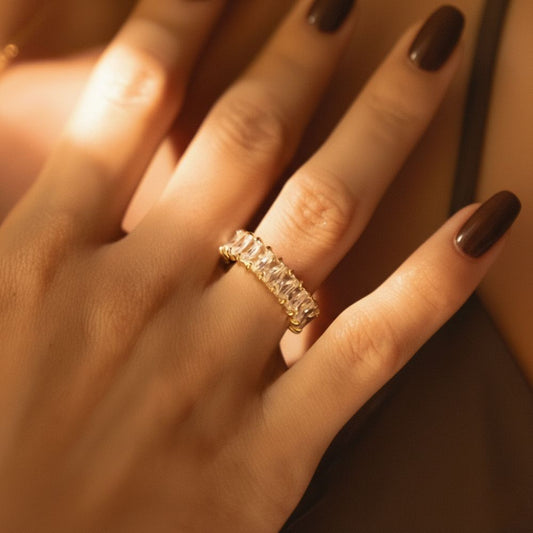 Astra Ring worn on hand, gold baguette crystal eternity band in warm light