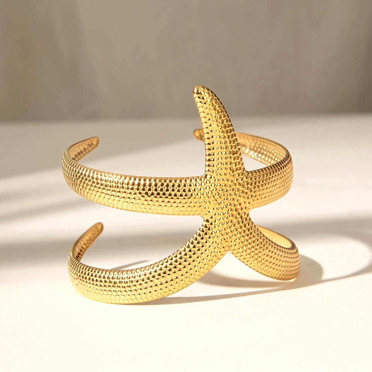 Starfish cuff bracelet styled with gold and pearl jewelry on dark skin