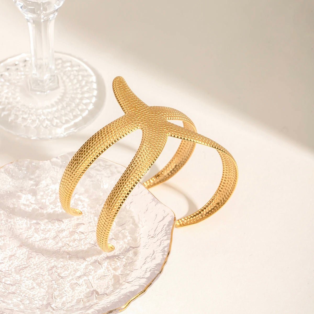 Elegant gold starfish cuff bracelet resting on a decorative plate