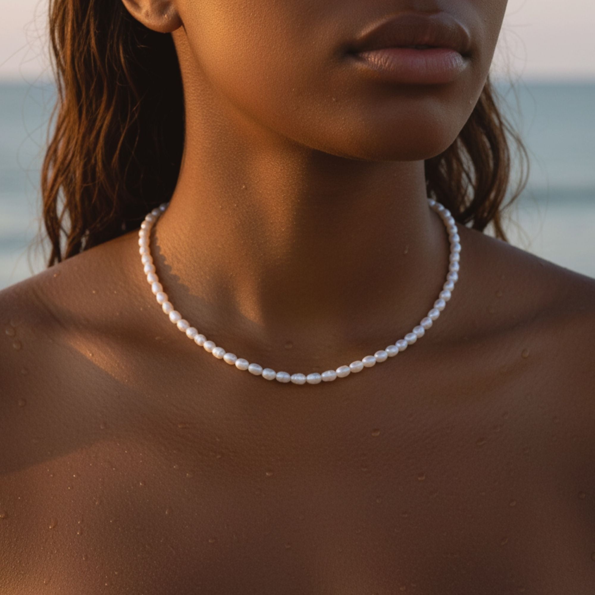  A wet caucasian model wearing the freshwater pearl necklace from Beach Bloom Jewelry at the beach.