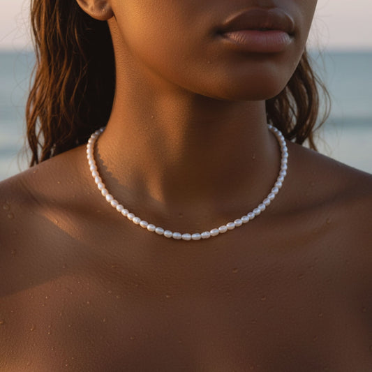 A black woman who wear a freshwater pearl necklace, at the beach 