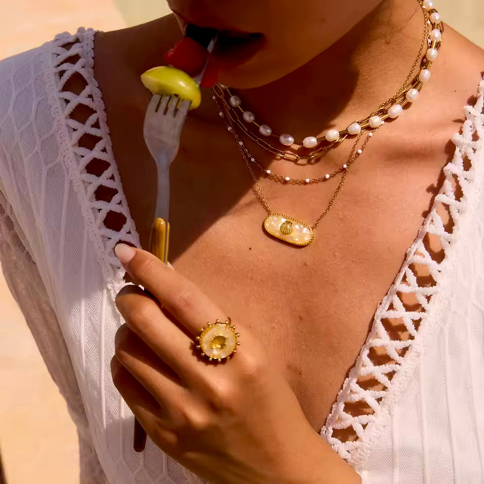 Front view of a colorful broken shell necklace in blue-green, pink and yellow tones, with a gold seashell charm.