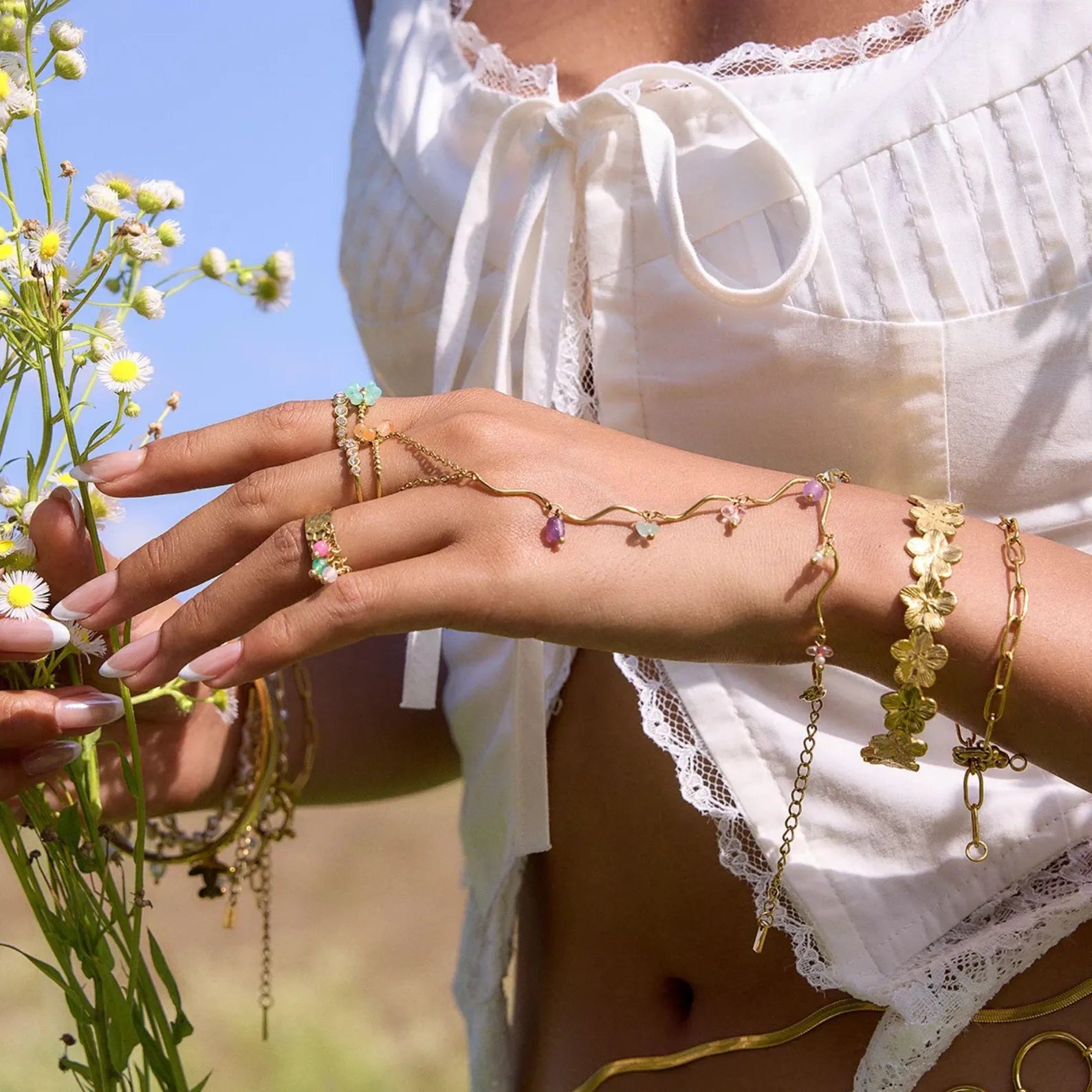 Gold hand chain bracelet with multicolor beads styled outdoors on model’s hand