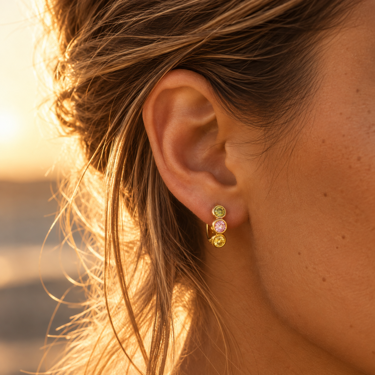 18K gold plated colorful huggie earring with pink, green and yellow stones worn on ear
