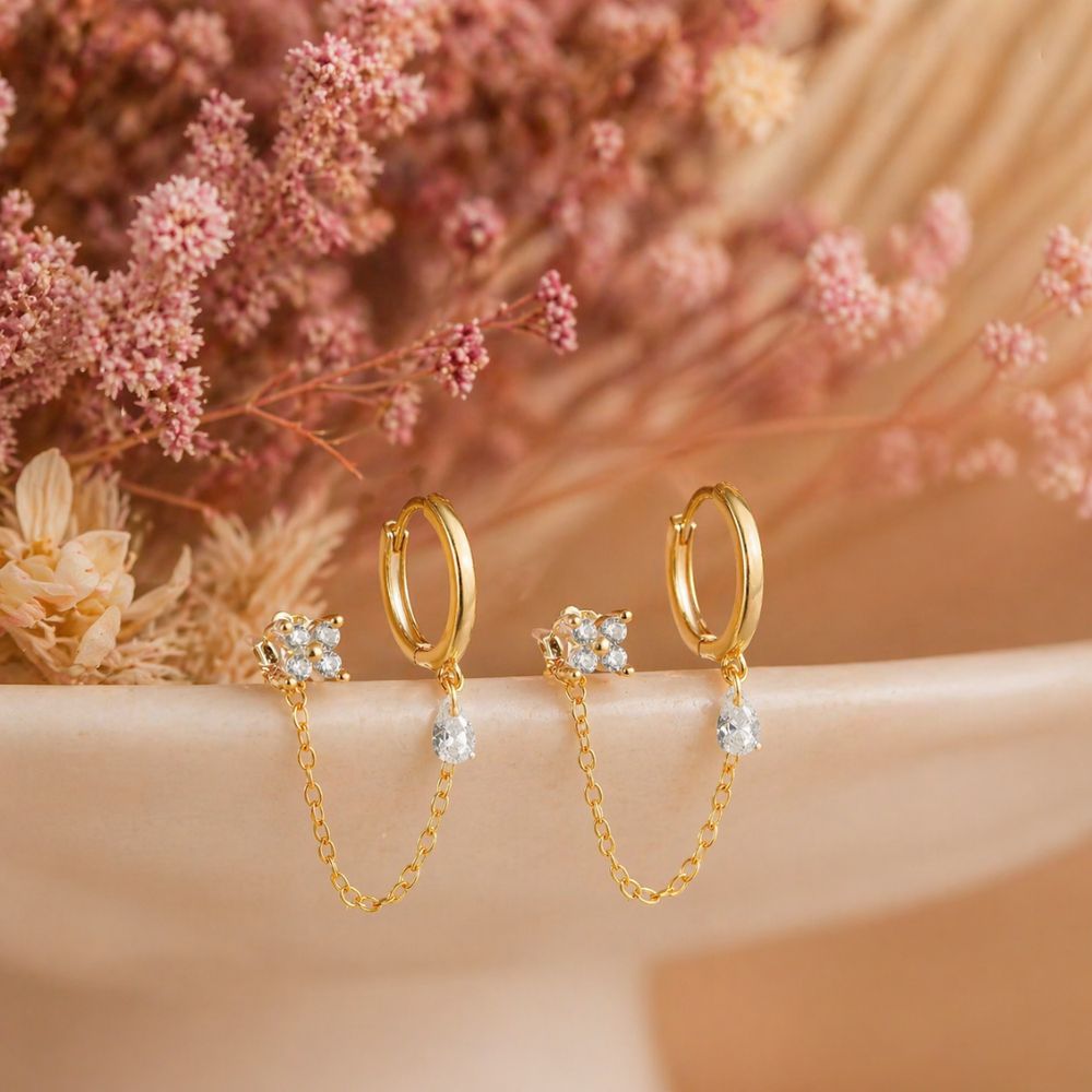 Pair of gold double piercing chain earrings with CZ stud hoop and chain on aesthetic background