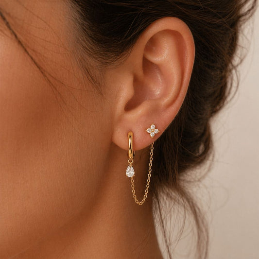 Gold double piercing chain earring worn on two lobe piercings with CZ stud and teardrop charm