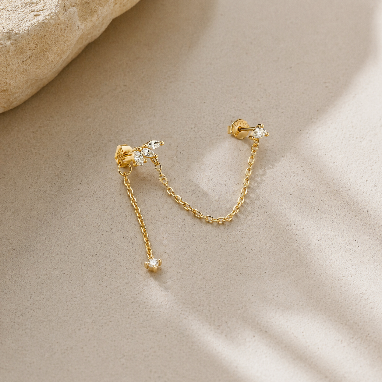 gold double piercing chain earrings with CZ studs and delicate chain on neutral background