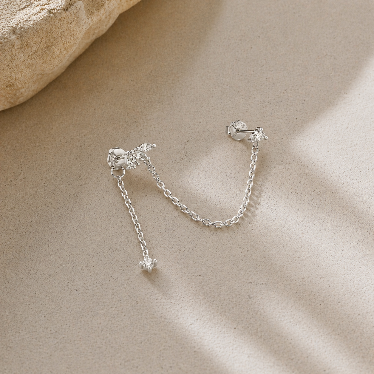 silver double piercing chain earrings with CZ studs isolated on neutral background