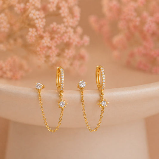 Gold double piercing chain pavé hoop earrings pair with CZ stud and north star charm on neutral background