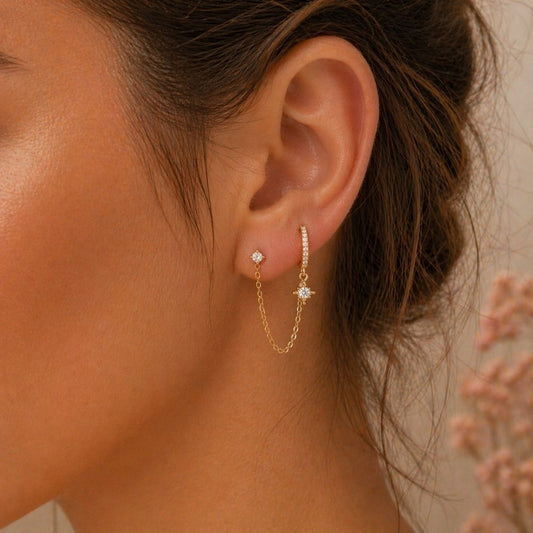 Close-up double piercing chain pavé hoop earring in gold worn on two lobe piercings with CZ stud and hoop