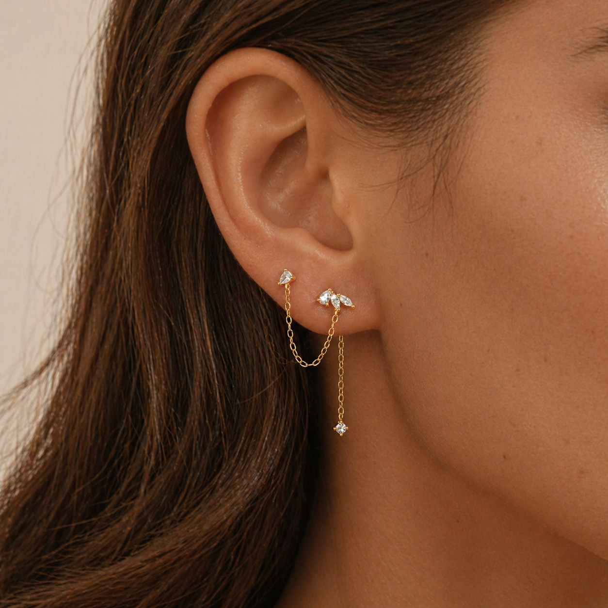 gold double piercing chain stud earrings worn on two lobe piercings with delicate chain