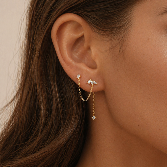 gold double piercing chain stud earrings worn on two lobe piercings with delicate chain