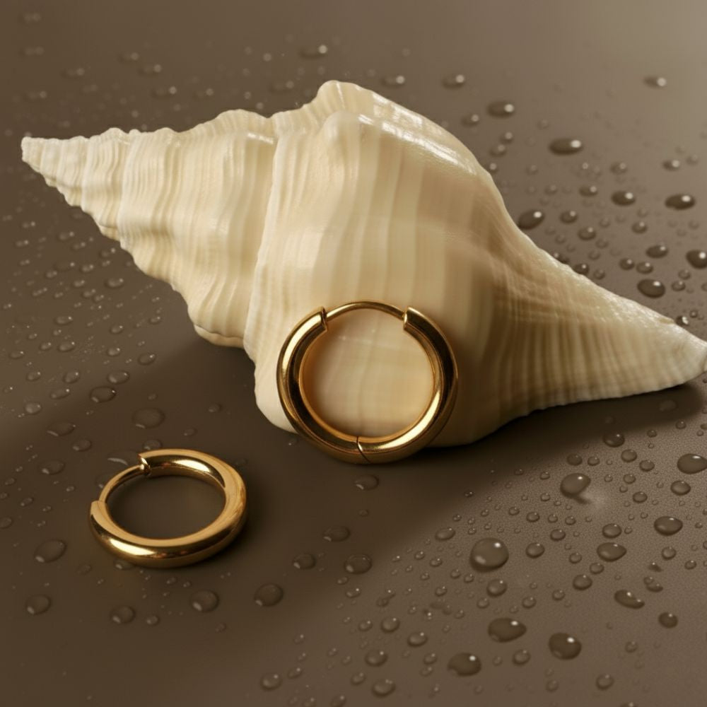 Essential hoop earrings displayed on a shell with water droplets
