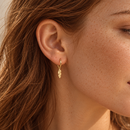 Dainty gold feather huggie earring on the lobe, 925 sterling silver
