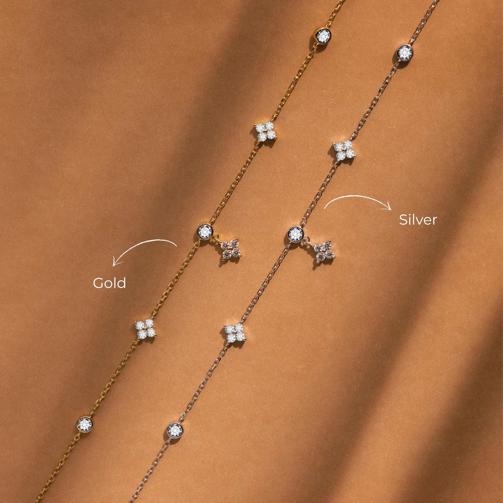 Gold and silver daisy station necklaces side by side on a warm brown background
