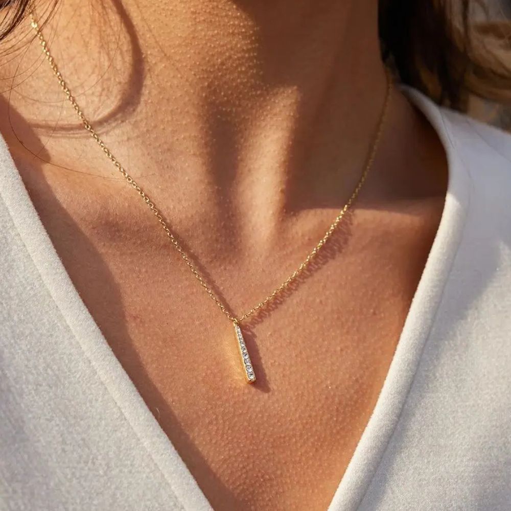 Woman wearing a dainty gold bar necklace stainless steel minimalist jewelry