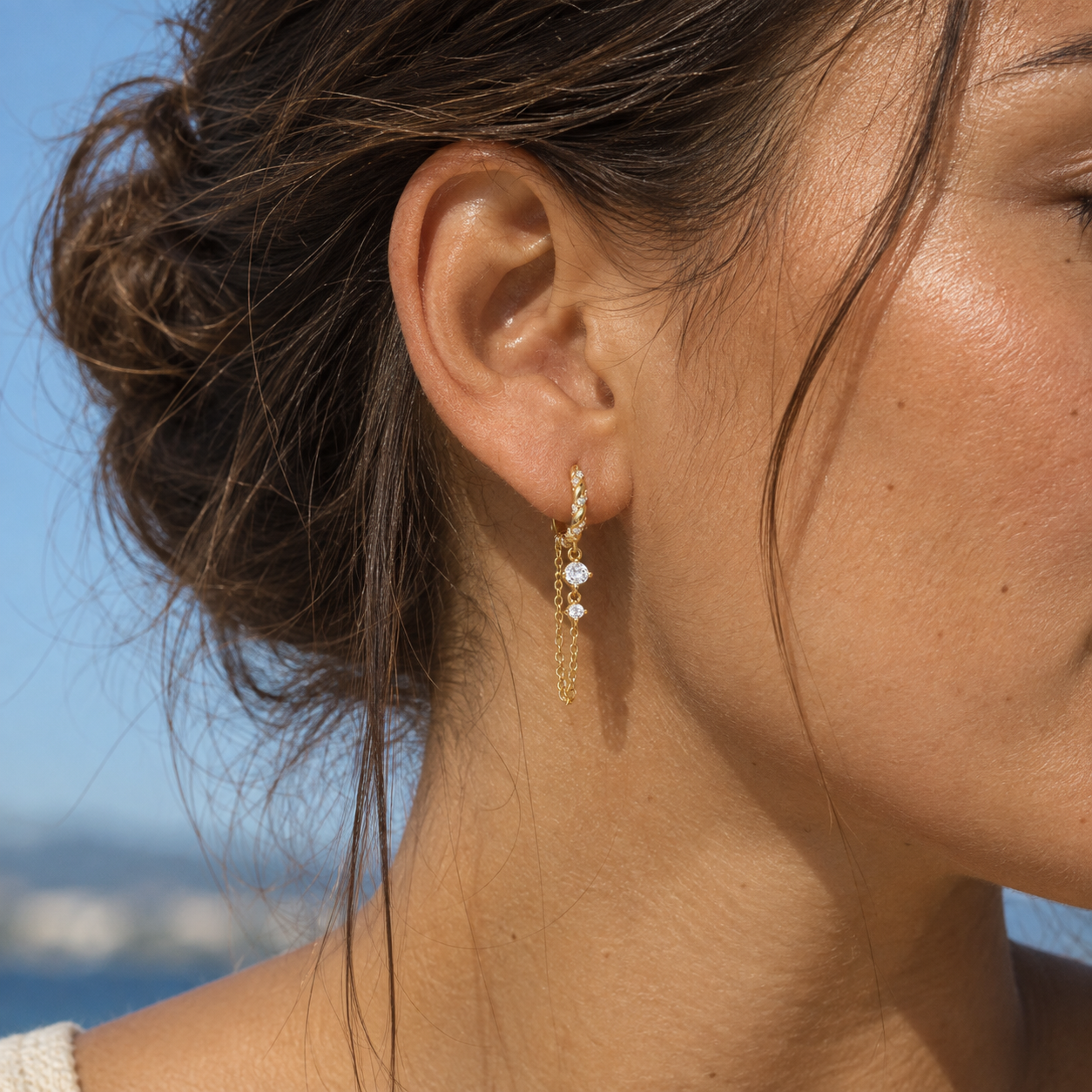 Gold chain drop earrings with cubic zirconia worn on a woman