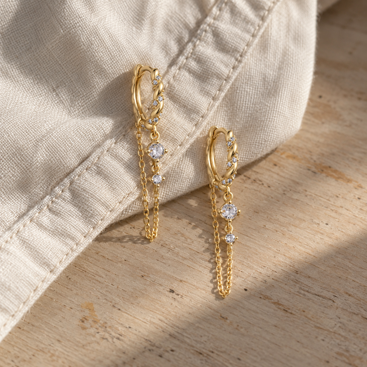 Pair of gold chain huggie earrings with dangling crystal stones