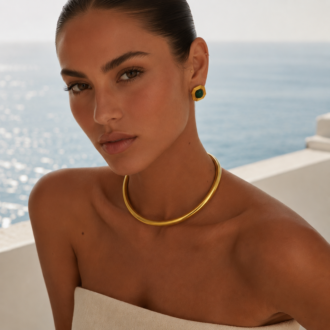 Woman wearing a gold collar necklace by the ocean
