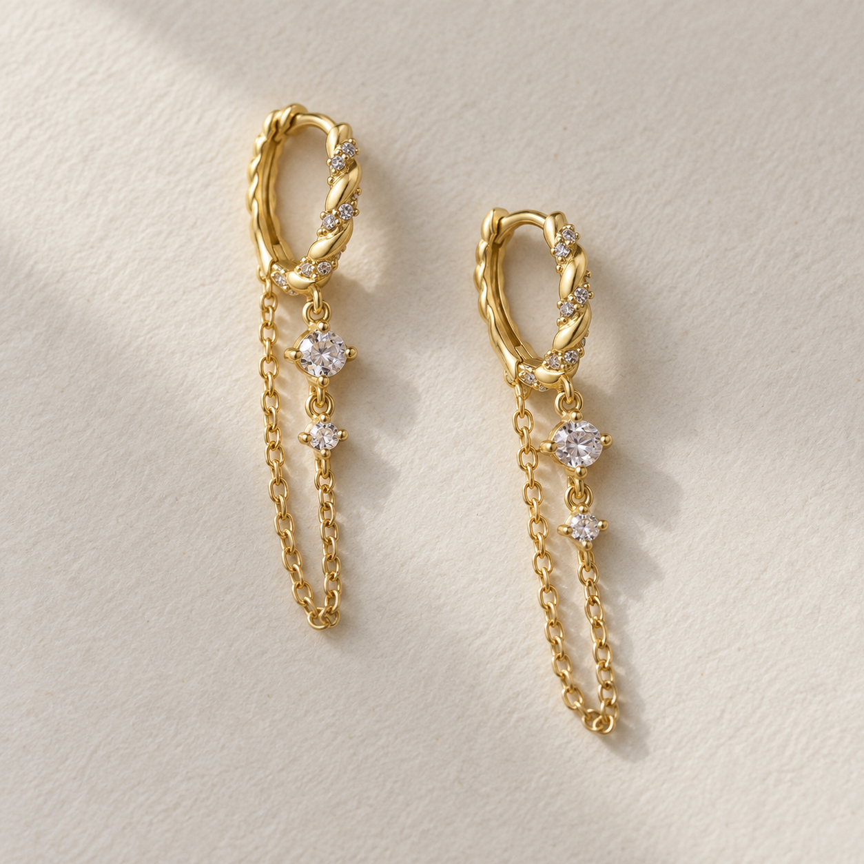 Pair of gold crystal chain drop earrings on a neutral background