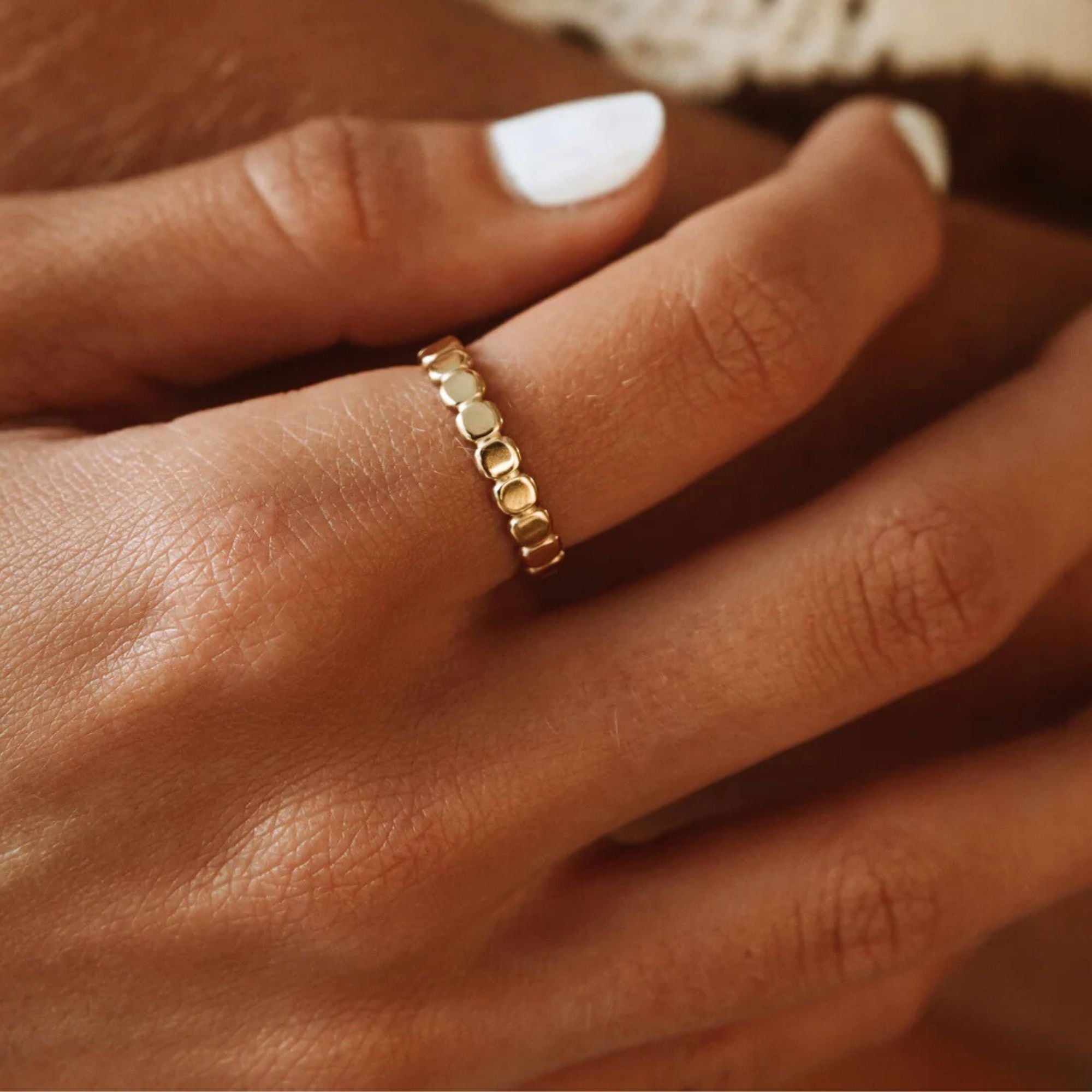 Delicate golden beads ring worn on hand, showcasing minimalist and elegant design.