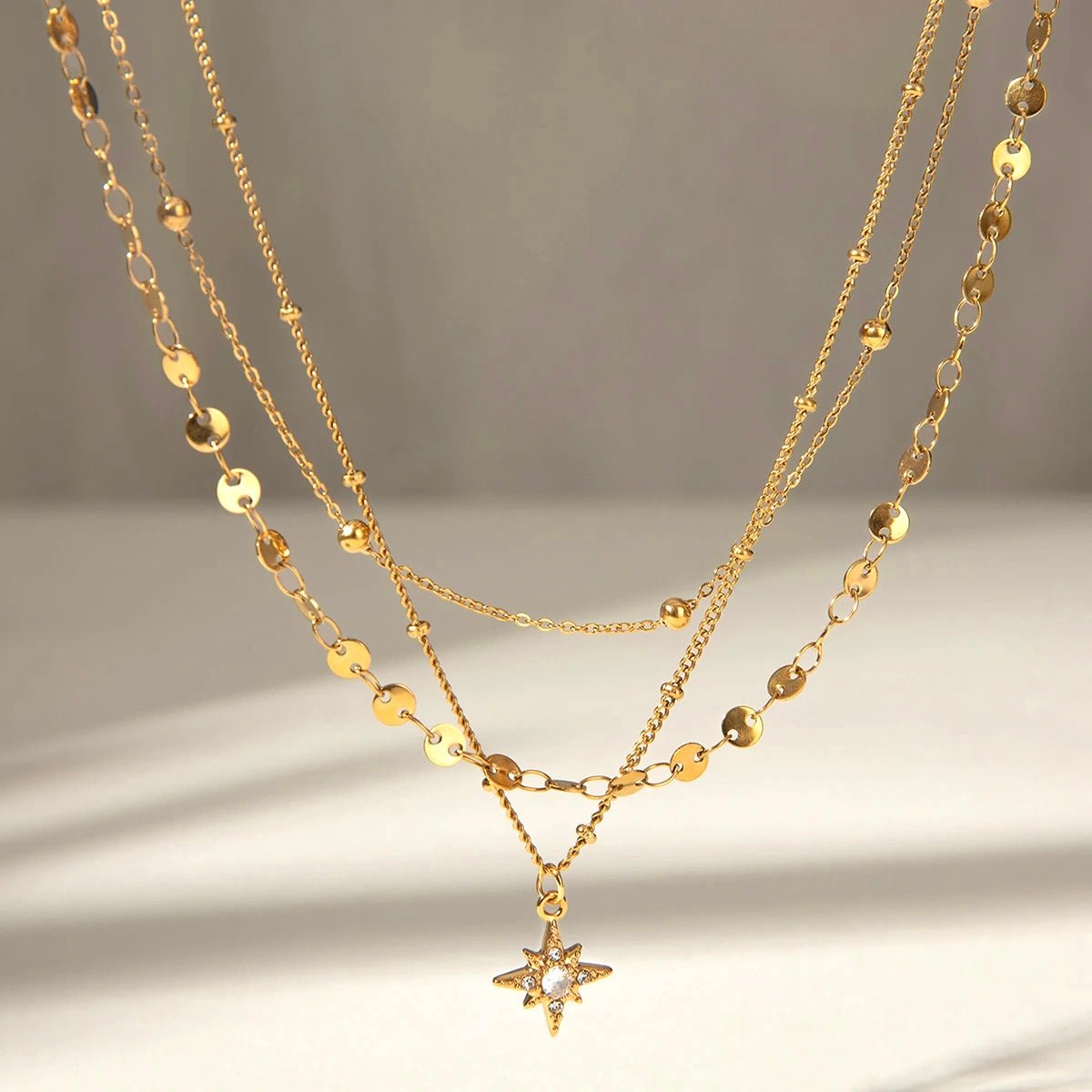 Close-up of layered gold necklace with reflective disc chains