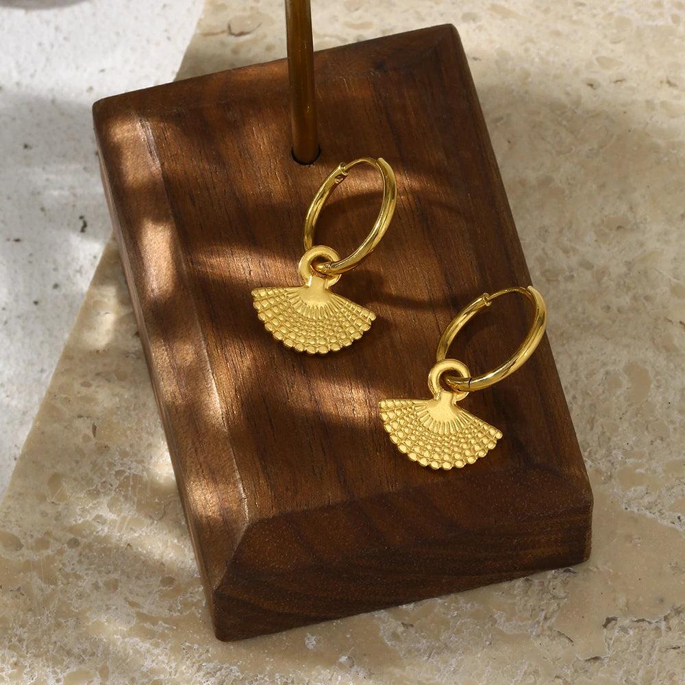 Gold fan hoop earrings with pendant presented on wooden jewelry stand