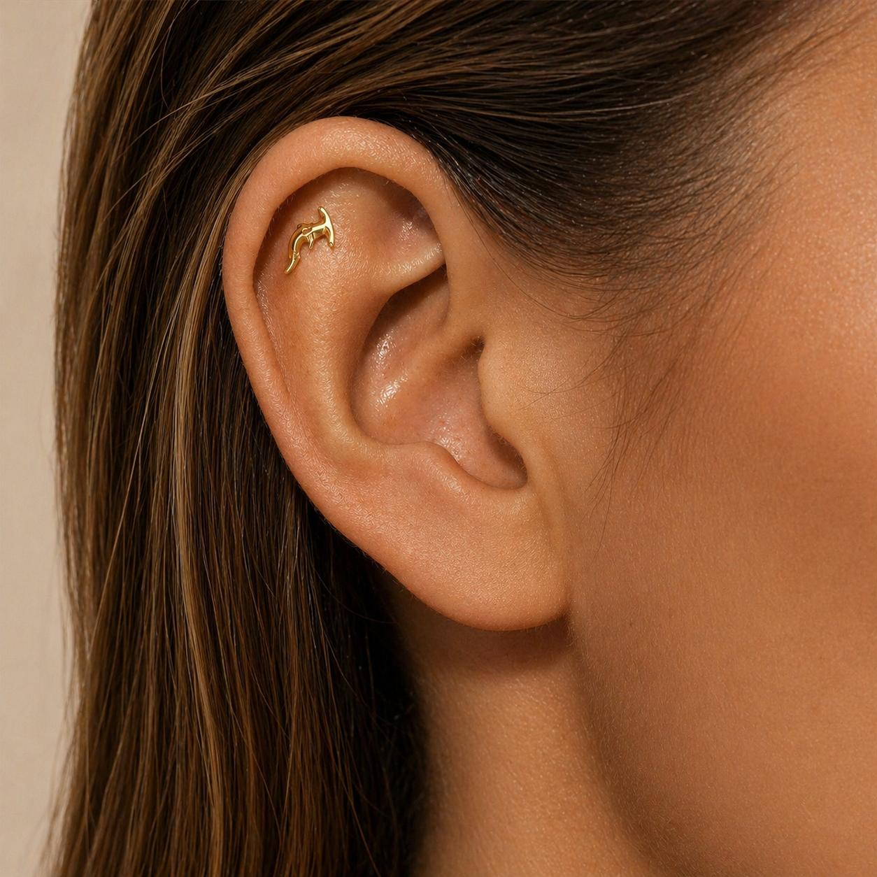 Gold hammerhead shark stud earring worn on helix piercing in ear