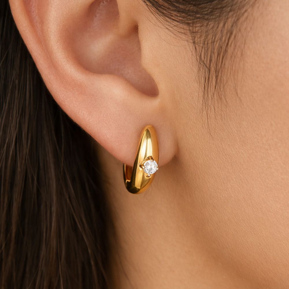 Gold huggie hoop earrings with white zircon worn on ear, minimalist waterproof stainless steel jewelry
