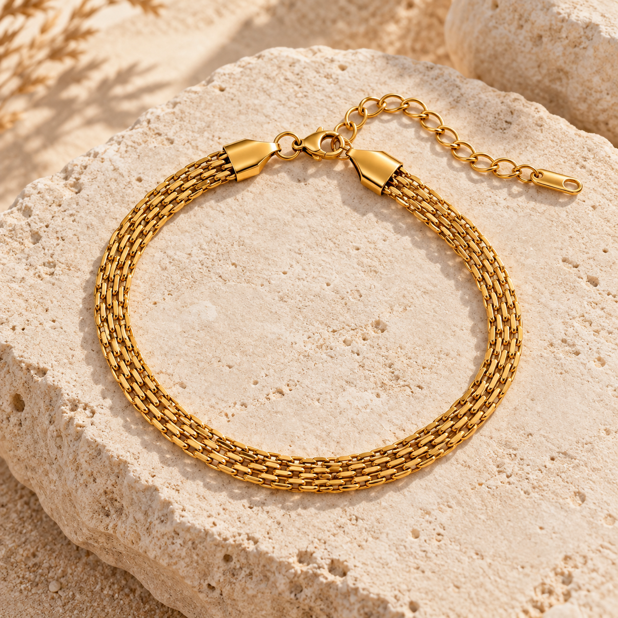 Gold layered chain anklet displayed on a textured beige stone