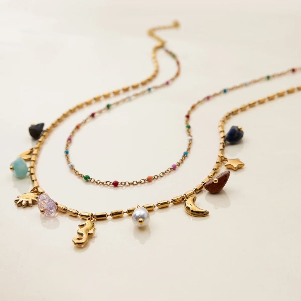 Close-up of layered gold charm necklace with colorful beads, summer jewelry detail