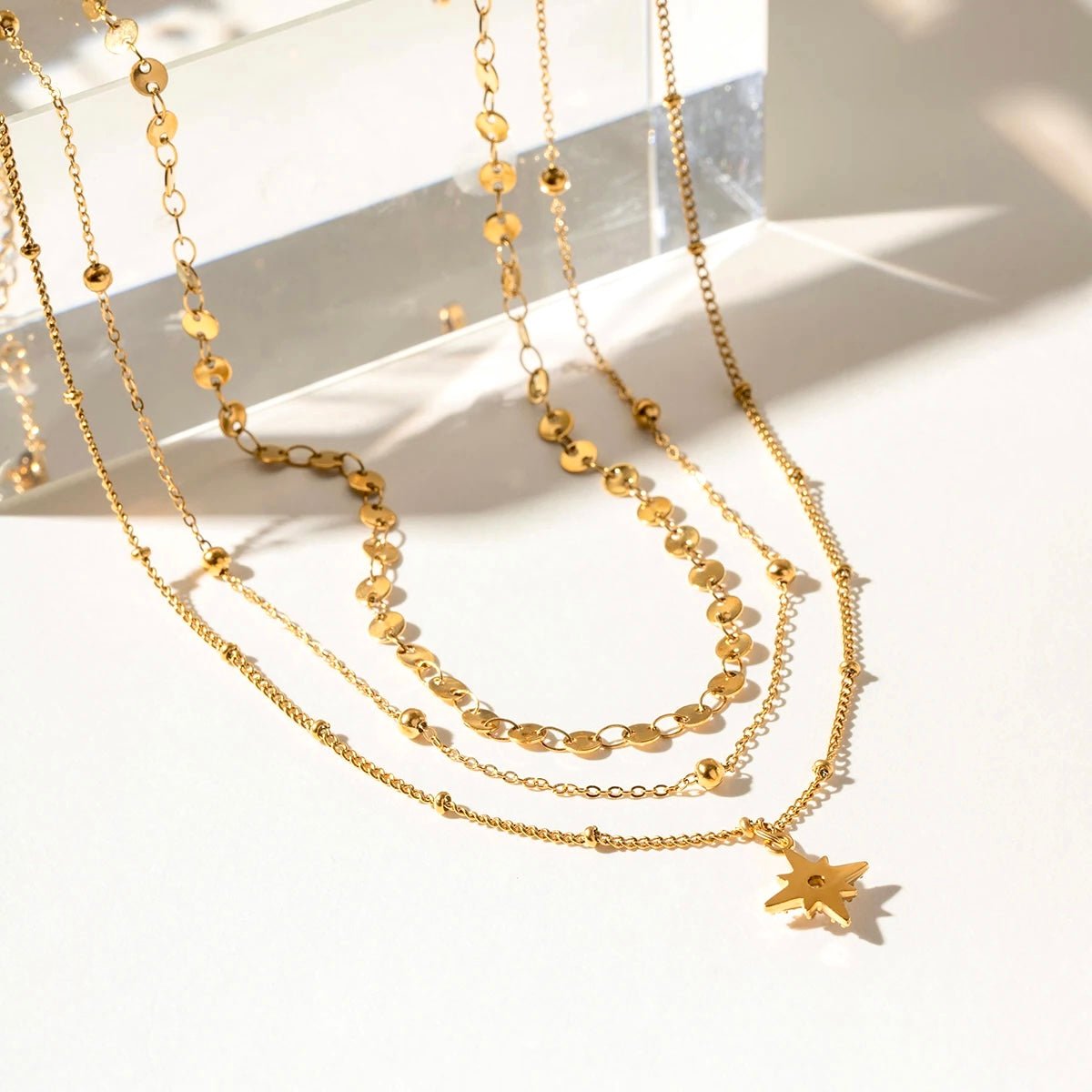 Flatlay of gold multi-chain star pendant necklace on white background