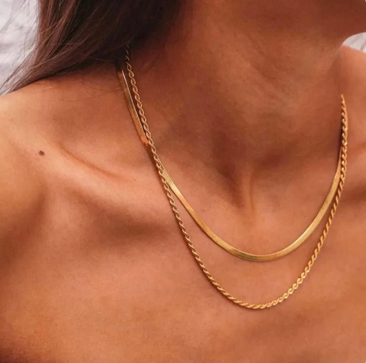 Layered 18k gold necklace worn on bare skin in natural light