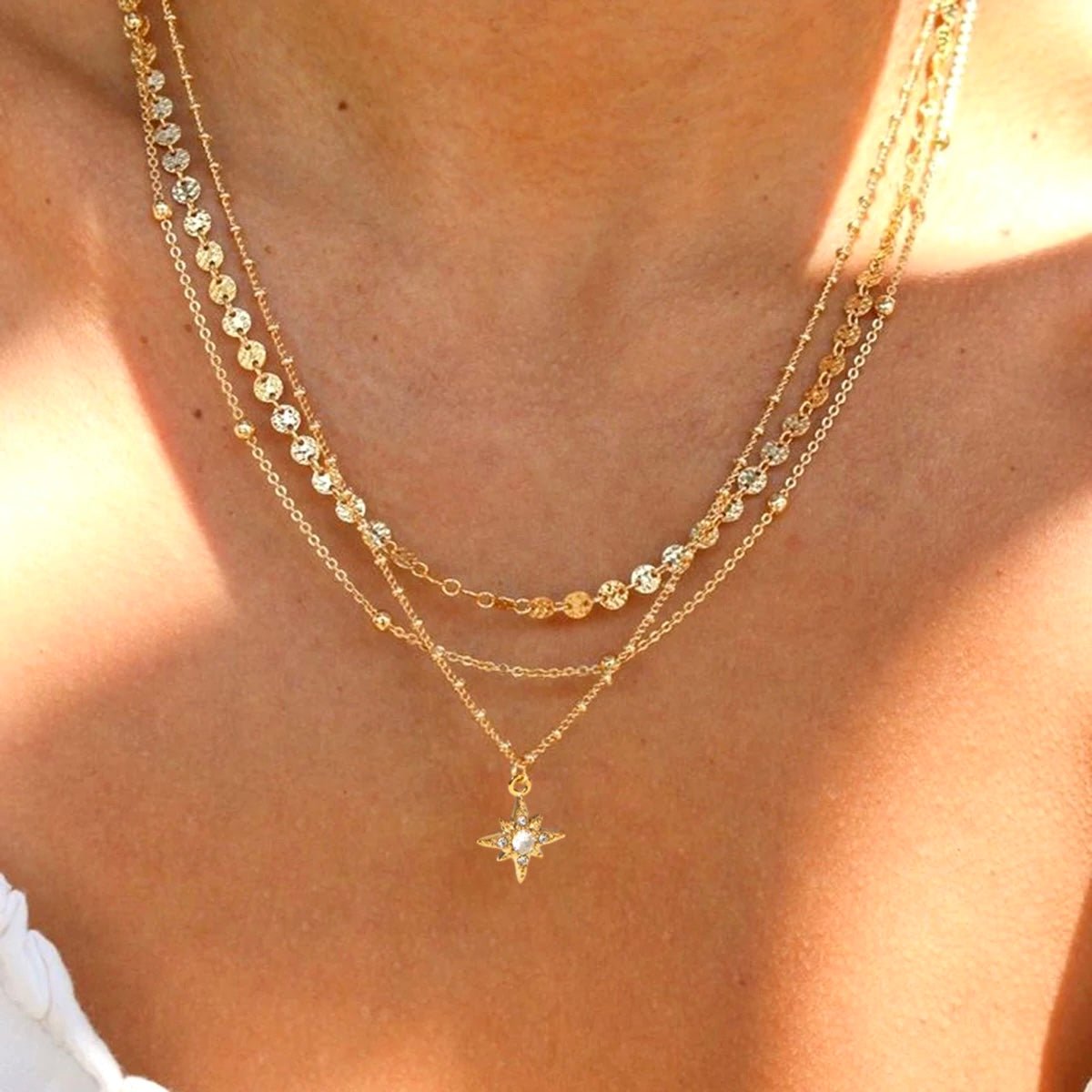 Close-up of layered gold necklace with reflective disc chains