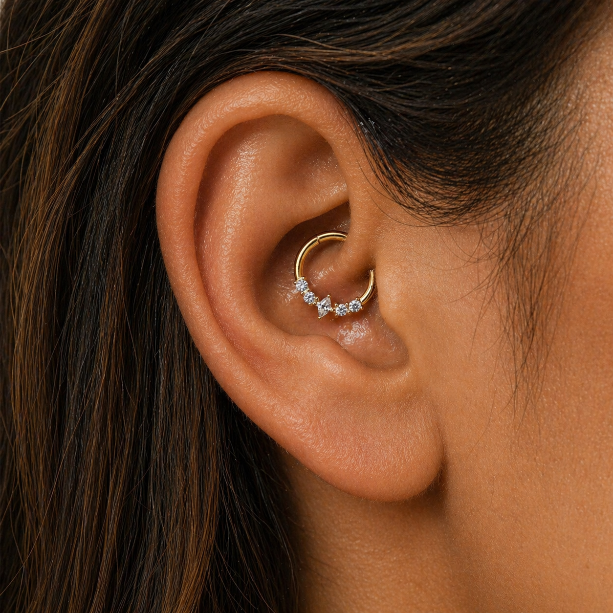 Close-up of gold marquise daith hoop earring with cubic zirconia stones worn in inner ear piercing