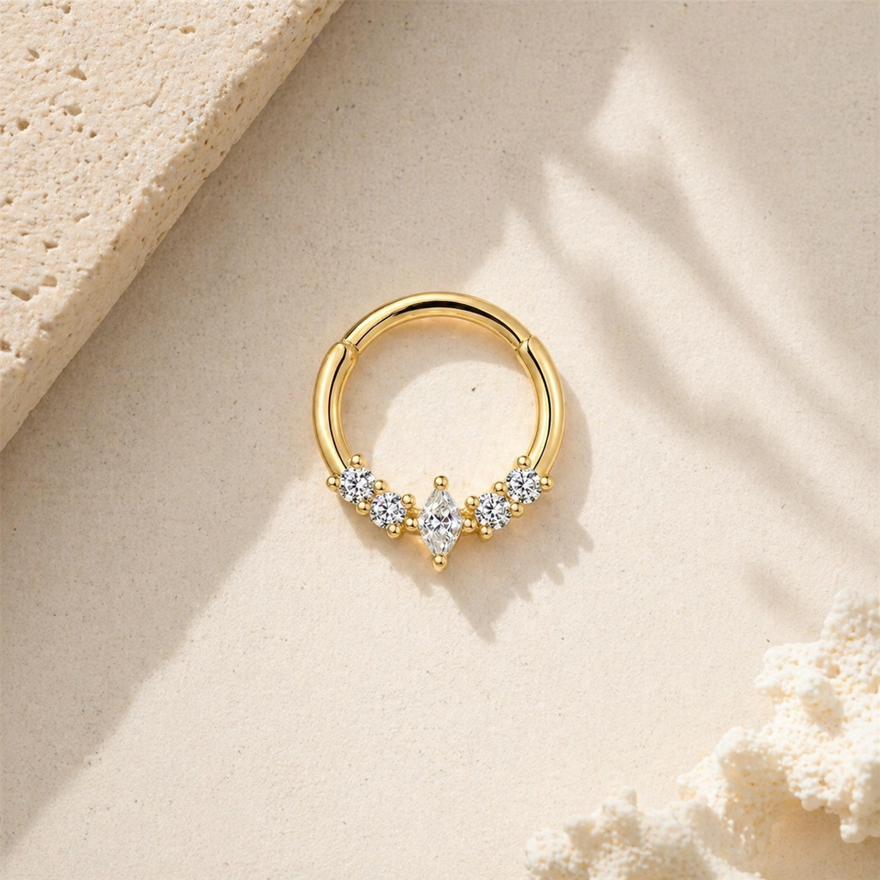 Gold marquise daith hoop earring with cubic zirconia stones on neutral beige background