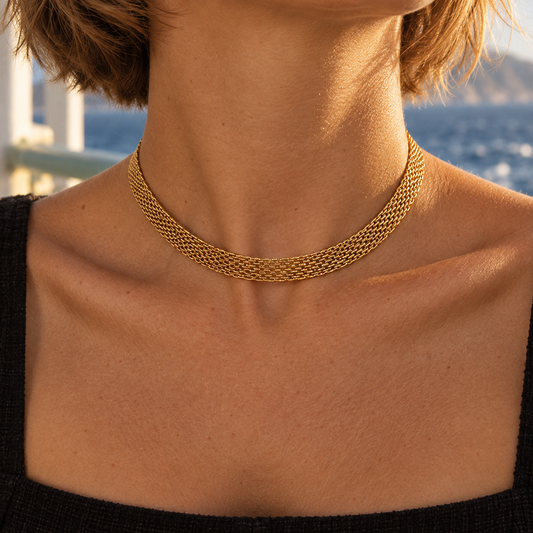 Close-up of a gold mesh choker necklace worn around the neck, showing its flat woven links.