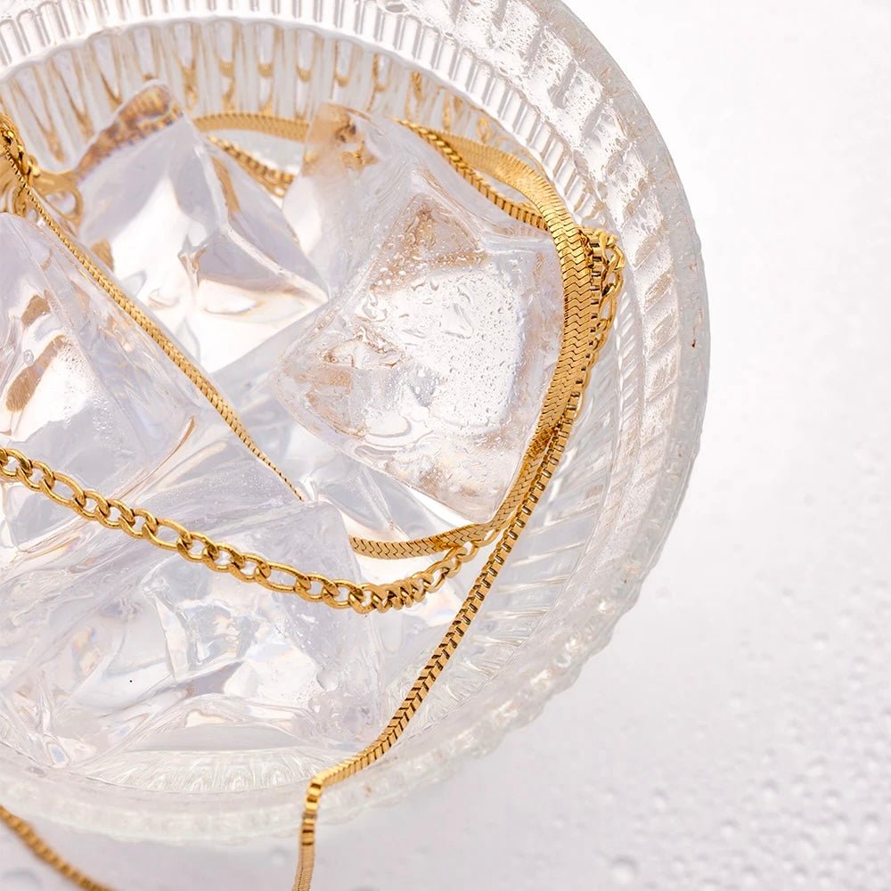 Triple gold chain necklace styled on ice cubes, showcasing waterproof feature