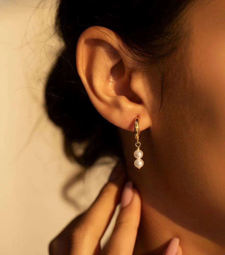 Gold pearl drop hoop earrings with double pearl dangle worn on ear, minimalist waterproof bridal jewelry