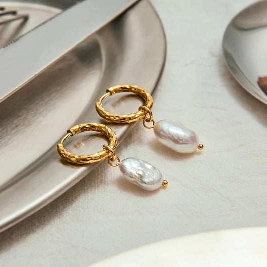 Flatlay of gold hammered hoop earrings with natural pearls on a silver setting
